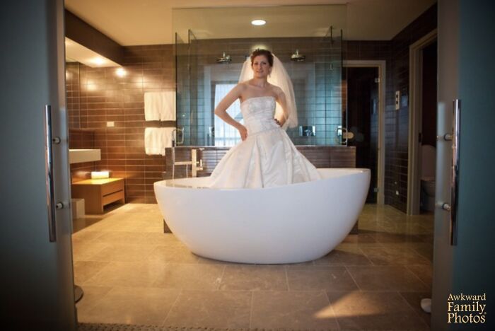 Novia con vestido de boda dentro de una bañera moderna en un baño elegante, foto de boda divertida y equivocada.