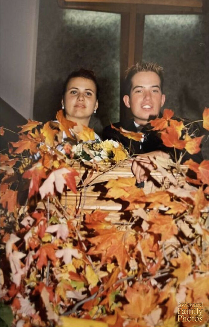 Bride and groom awkwardly posing behind fall leaves, creating one of the most memorable awkward wedding photos in autumn setting.