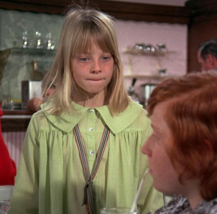 Young girl in a green dress looking serious, representing Jodie Foster saved from Hollywood predators as a child.