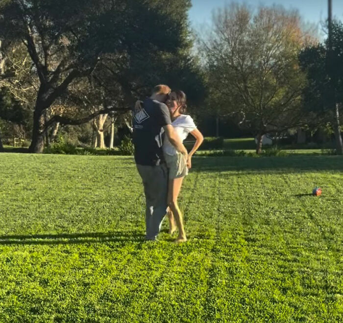 Couple embracing outdoors on green grass with trees in background, related to Meghan Markle 2016 throwback post controversy.