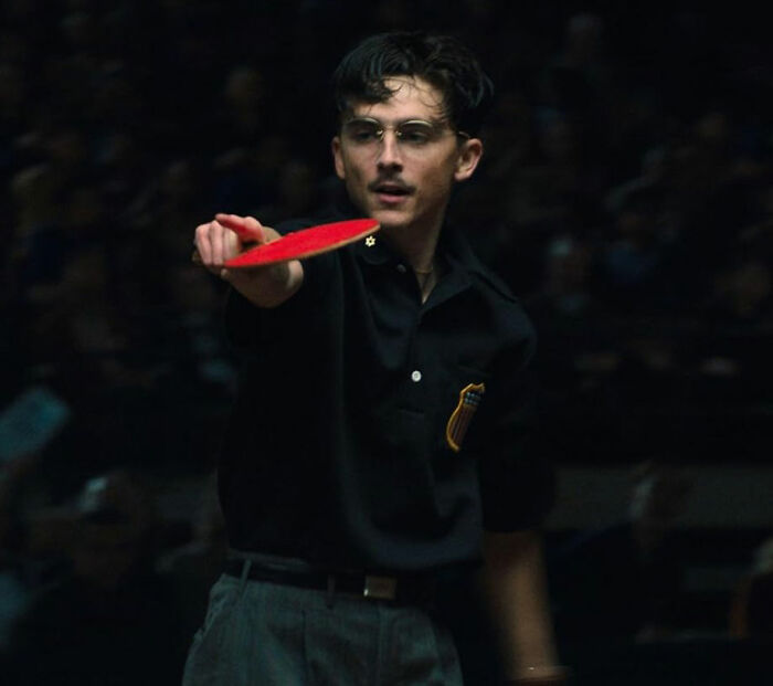 Young man playing table tennis intensely, showcasing focus and skill in a dimly lit indoor setting for Oscar nominations. Young man playing table tennis intensely, showcasing focus and skill in a dimly lit indoor setting for Oscar nominations.