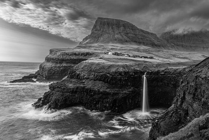 Coastal landscape with a waterfall pouring into the ocean, featured in stunning animal photos from Exposure One awards.