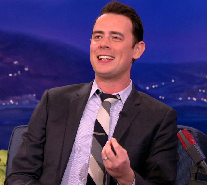 Man in suit and tie smiling during interview, related to movie set workers sharing biggest diva stars experiences.