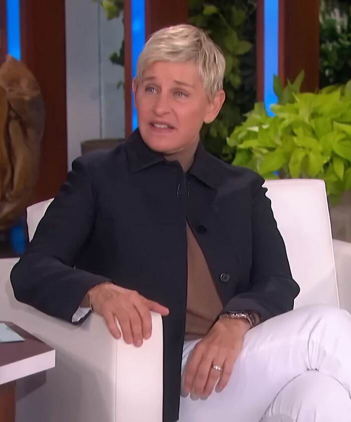 A person with short blonde hair sitting on a white chair during an interview about diva stars on movie sets.