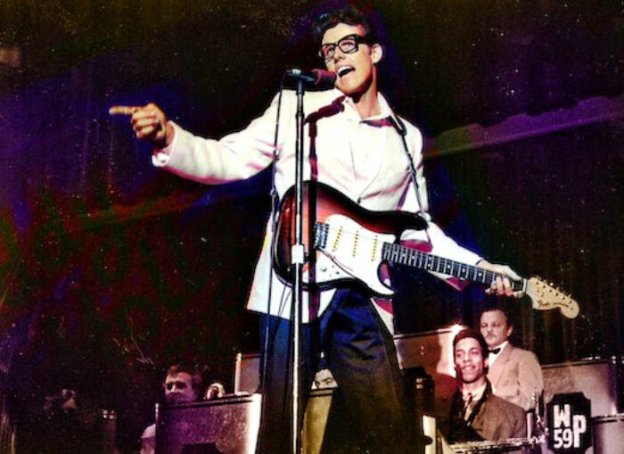 Musician performing on stage with guitar and microphone, representing celebrity downfalls in entertainment.