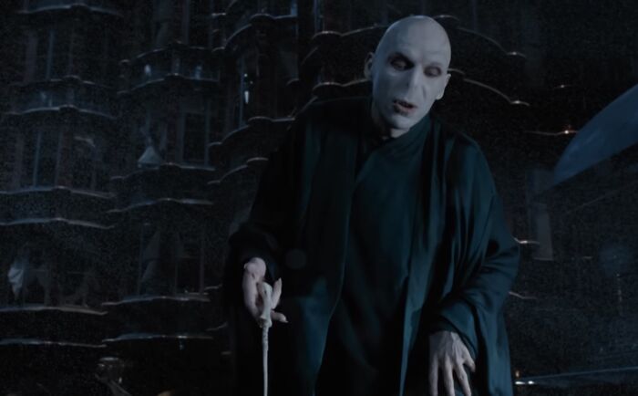 Lord Voldemort holding a wand outside a dark castle, representing pure evil from famous villain characters.