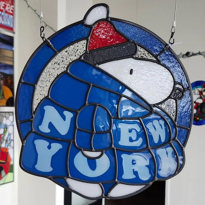 Stained glass sign of a pop culture icon wearing a winter hat with New York letters in blue and white colors.