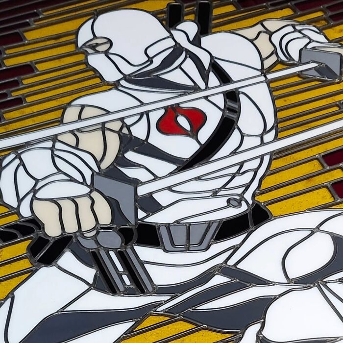 Vivid stained glass sign of a pop culture icon in white armor holding weapons against a yellow and red background.