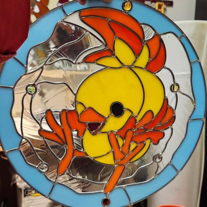 Vivid stained glass sign featuring a colorful yellow and orange pop culture icon bird with blue border.