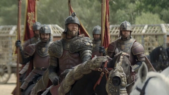 Knights in armor carrying banners featuring house sigils from a fantasy medieval setting in a Knight of the Seven Kingdoms.