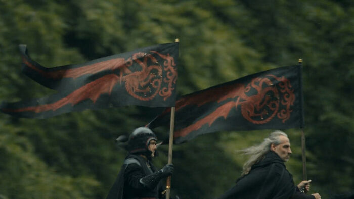 Two riders carry black flags with red dragon house sigils, representing every house sigil in A Knight of the Seven Kingdoms.