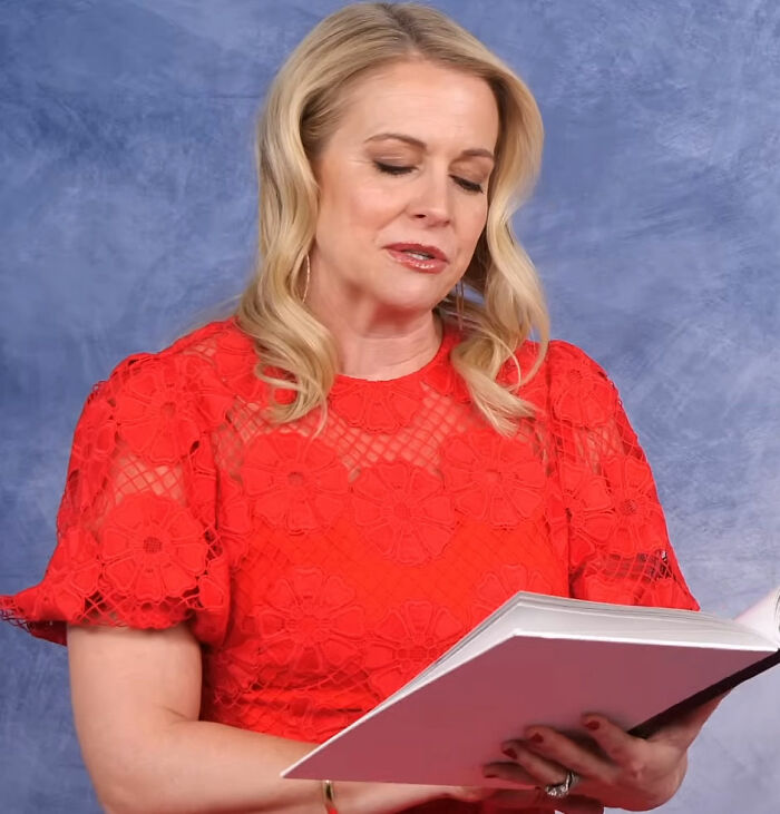 Woman in a red lace dress reading a book, reflecting on a Nickelodeon star's humiliating moment with Britney Spears.