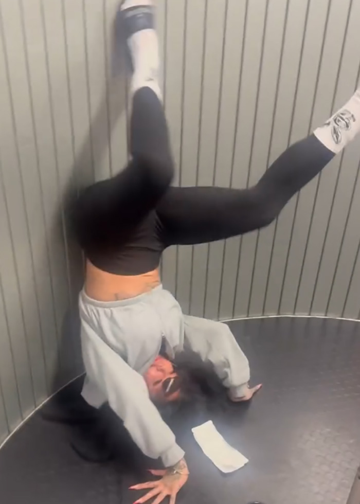 Person doing a handstand wearing black leggings and gray sweatshirt, related to adult stars arrested and first-class seats incident