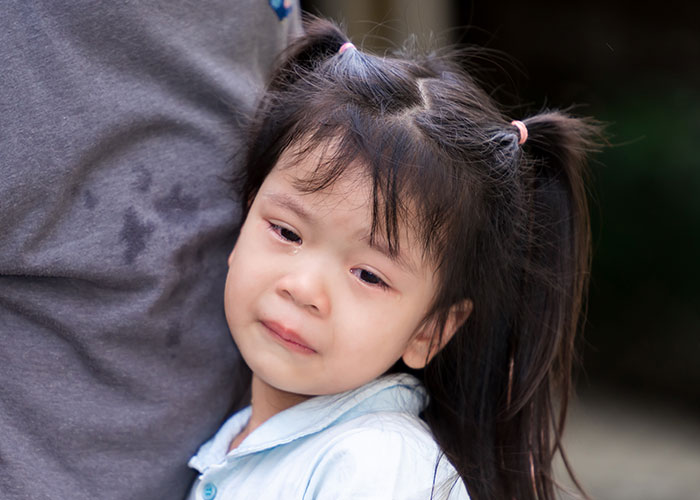 Young girl with tears hugging adult, capturing heartbreaking and sad goodbyes at the airport moment.