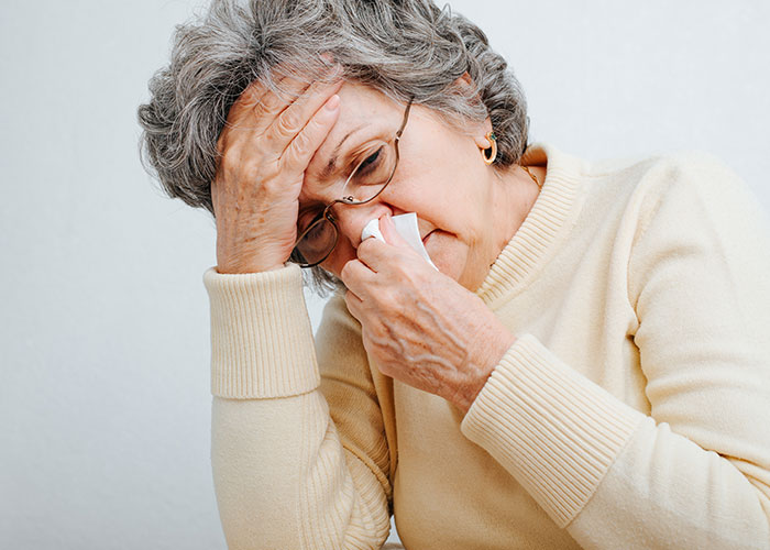 Elderly woman emotionally wiping tears, showing heartbreaking and sad goodbyes at the airport moment.