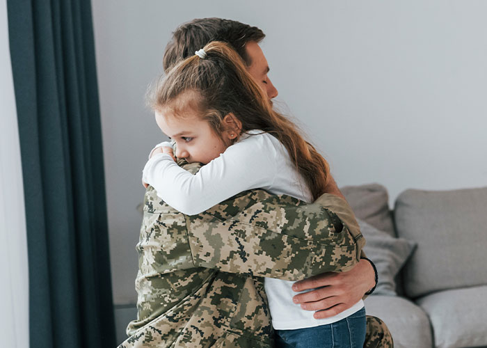 Soldier in camouflage uniform hugging a young girl, capturing one of the most heartbreaking and sad goodbyes at the airport.