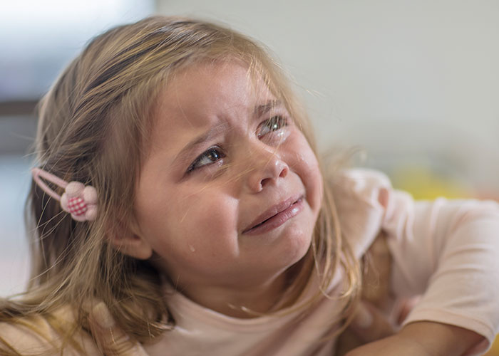 Young girl crying with tears streaming down her face, capturing a heartbreaking and sad goodbye at the airport moment.