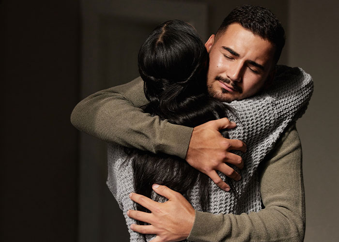 Young couple sharing a heartbreaking and sad goodbye hug at the airport, expressing deep emotion and connection.