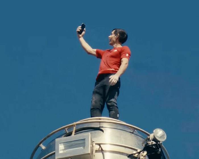 Famous climber standing atop skyscraper, taking a selfie during 500-meter climb amid Netflix pay backlash.