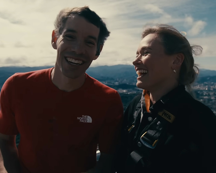 Two climbers smiling outdoors with cityscape background, highlighting Netflix faces backlash for skyscraper climb pay.