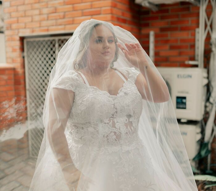 Bride in a white lace wedding dress and veil posing outdoors, capturing a candid moment from wedding moments.