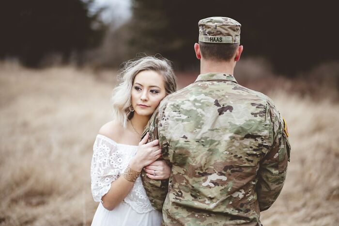 A couple embracing outdoors with the woman in a white dress and man in military uniform, symbolizing fastest times couples said I do.