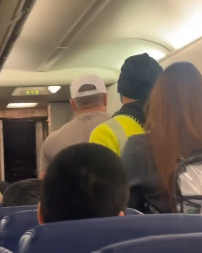 Bodybuilder being removed from flight after angry outburst at elderly passenger inside airplane cabin.