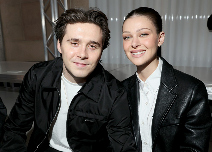 Nicola Peltz and Brooklyn Beckham smiling together at an event, amid Victoria Beckham and Nicola Peltz feud news.