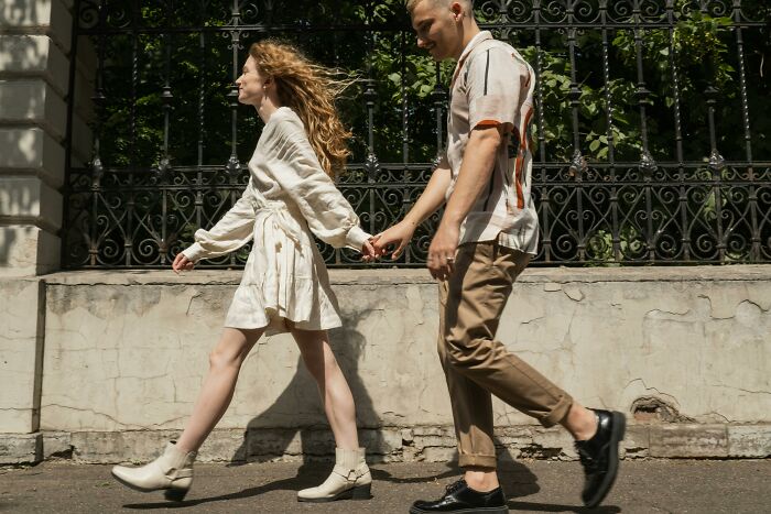 Couple holding hands and walking outdoors, illustrating dating gestures and relationship dynamics discussion.