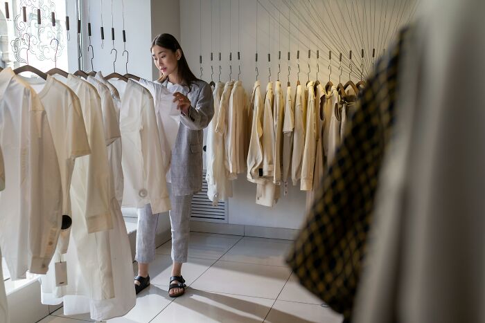 Woman browsing white shirts in a modern store, reflecting on dating gestures and whether we accept the bare minimum