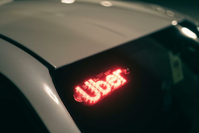 Close-up of a car with a glowing Uber sign, illustrating modern dating gestures and ride-sharing culture.