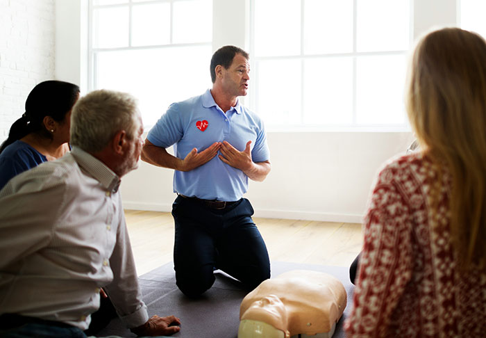 Instructor teaching CPR skills to a group of adults during a life improvement workshop focused on easy skills to retire rich.