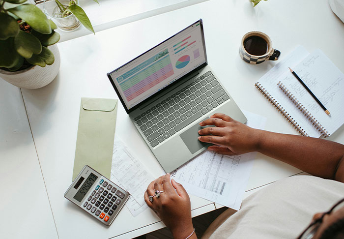Person using laptop with financial charts and calculator, focusing on skills to retire rich and improve life finances.