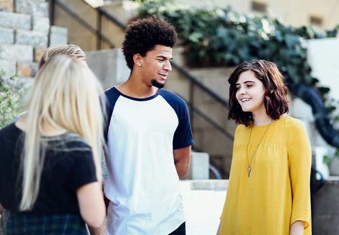 Group of young adults casually talking outdoors, illustrating easy skills to improve your life for a rich retirement.