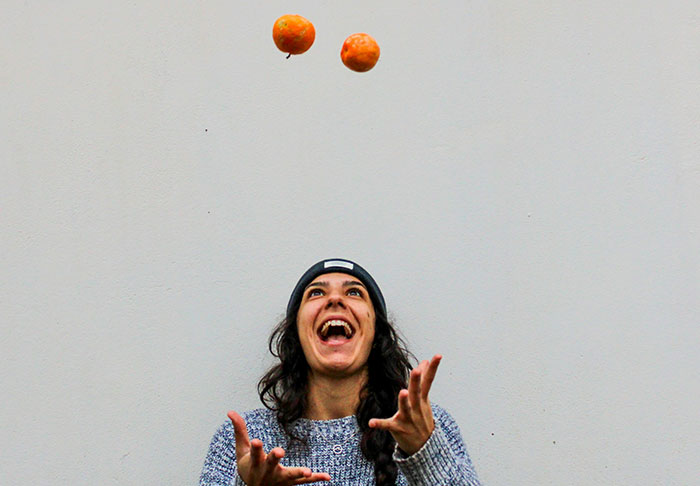 Person smiling and juggling oranges, symbolizing easy skills to improve your life for a richer retirement.