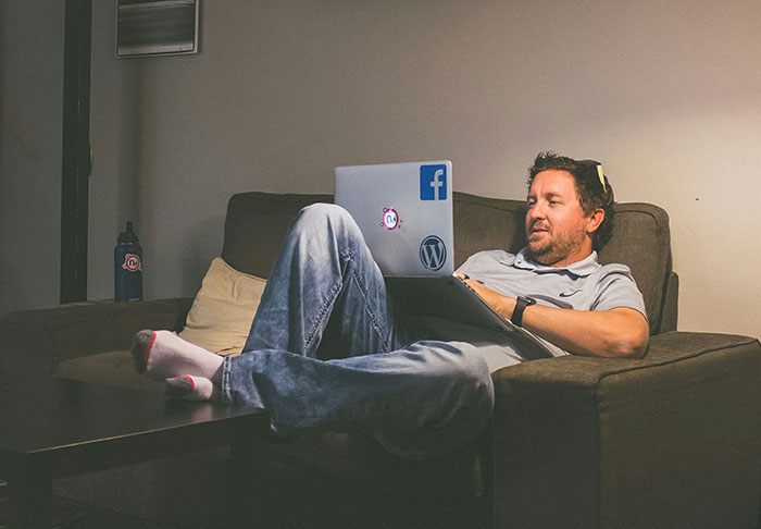 Man relaxing on a couch using a laptop, exploring easy skills to improve life and retire rich from home.