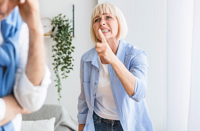 Extremely religious lady angrily confronting daughter's boyfriend in a home setting, making a firm point with her finger.