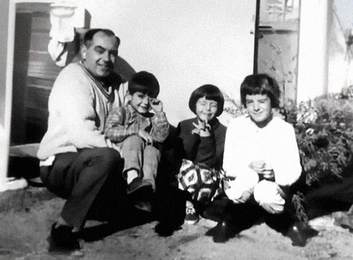 Black and white photo of a man and three children sitting outside, related to biggest unsolved cases worldwide.