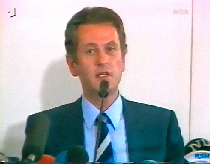 Man in suit speaking at a press conference about some of the biggest unsolved cases from all over the world