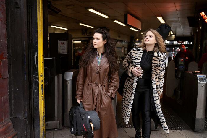 Two women at a subway entrance, capturing weird and awkward moments bilingual people caught gossiping about them.