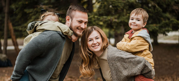 Happy teenage family spending time outdoors with children playing piggyback, representing teen refusing to live with bio parents. Happy teenage family spending time outdoors with children playing piggyback, representing teen refusing to live with bio parents.