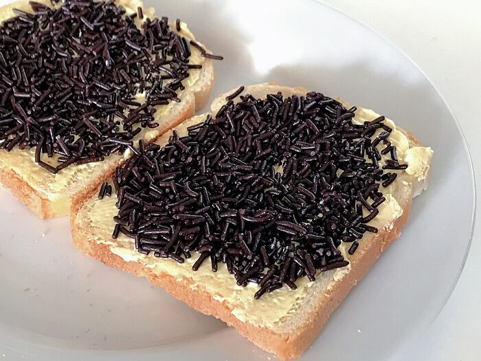 Two slices of bread with butter and chocolate sprinkles, an example of unusual local delicacies in food culture.
