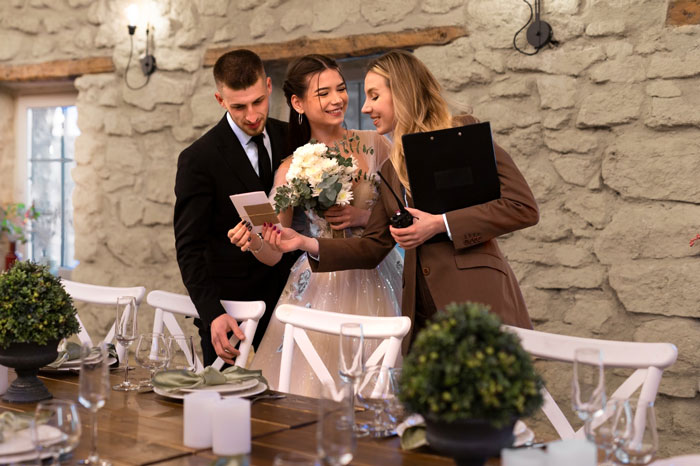 Three people reviewing a wedding invitation at a decorated table, depicting wedding date ownership conflict. Three people reviewing a wedding invitation at a decorated table, depicting wedding date ownership conflict.
