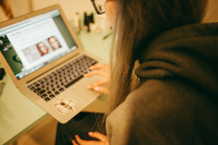 Person browsing a laptop, reading and sharing boomer opinions in a cozy indoor setting with warm lighting.