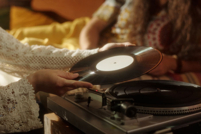 Person placing a vinyl record on a turntable, illustrating nostalgic boomer opinions on classic music formats.