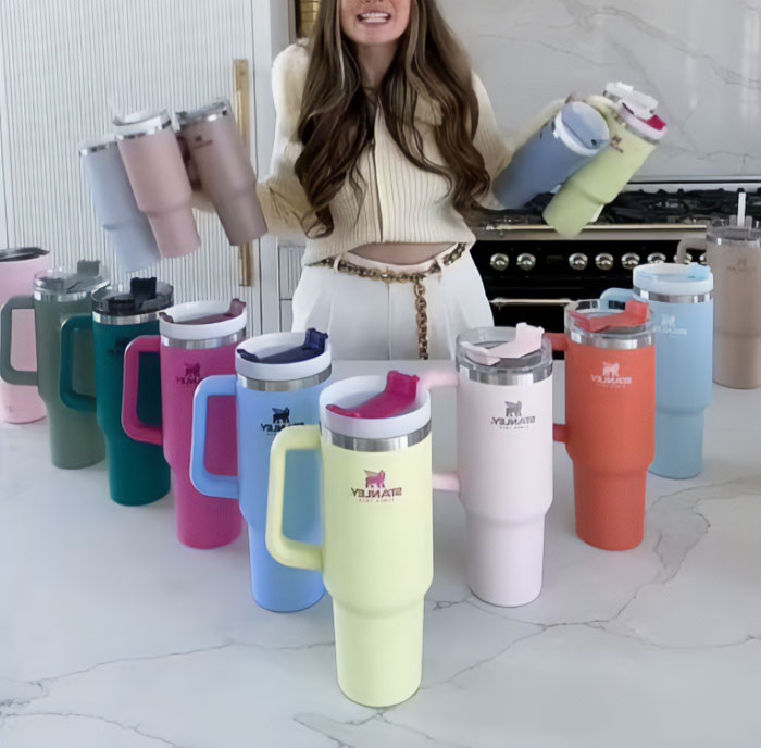 Woman in kitchen with colorful insulated tumblers, illustrating popular boomer opinions on drinkware and lifestyle trends.