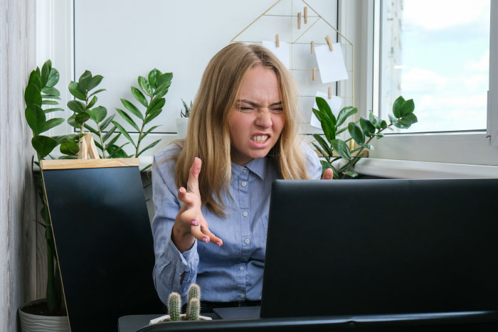 Young woman showing frustration while using laptop indoors, illustrating common boomer opinions in digital age discussions.