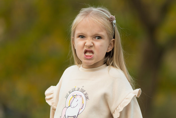 Young girl making a funny angry face outdoors, illustrating boomer opinions with a fierce expression.