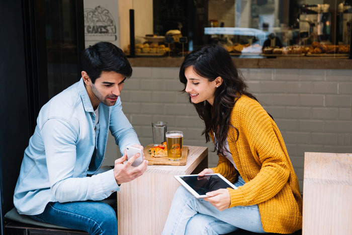 Bullied employee and boss sitting at cafe table, sharing a moment with phone and tablet, building unexpected rapport. Bullied employee and boss sitting at cafe table, sharing a moment with phone and tablet, building unexpected rapport.
