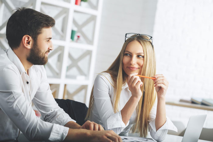 Man and female colleague sharing a private moment at work, hinting at relationship dynamics beyond professional boundaries.